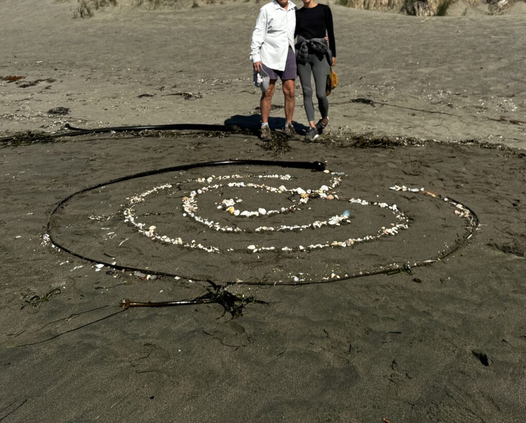 Two people standing in front of a labyrinth drawn on the ground.