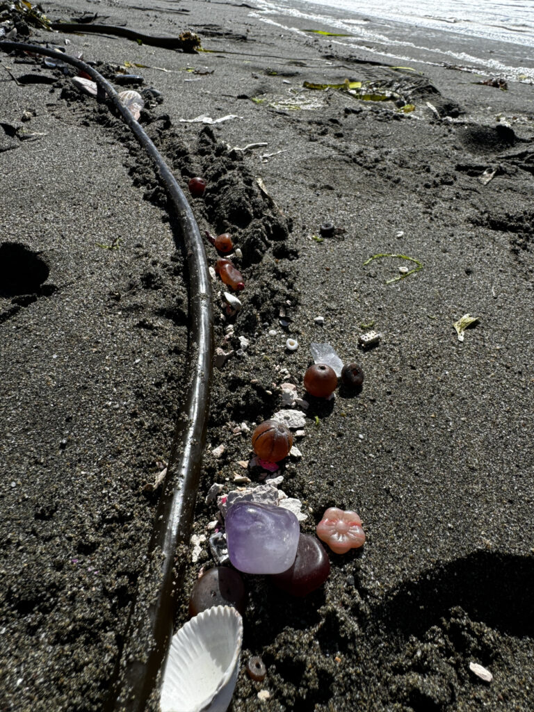 A broken water pipe on the beach with trash.