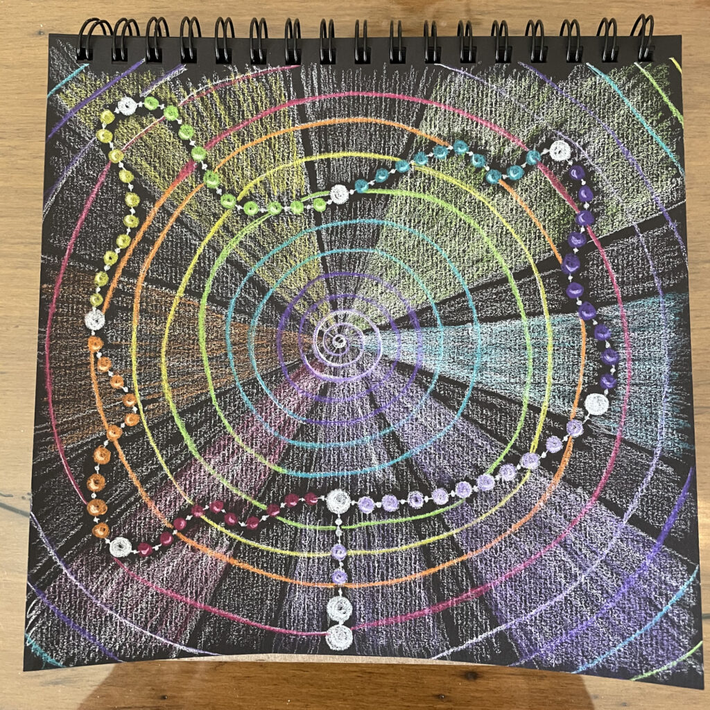 A spiral notebook with a colorful drawing of a circular pattern.